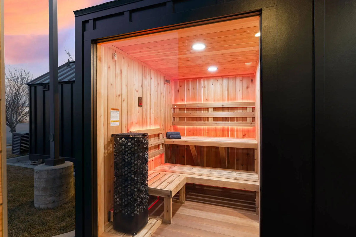 Wooden sauna with benches and a black exterior, surrounded by outdoor elements.