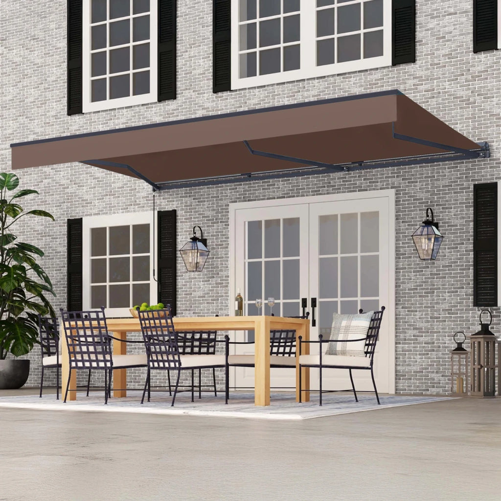 A brown retractable patio awning extends over a dining area on a house porch. The scene shows a gray brick home exterior with white-framed windows, black shutters, outdoor lanterns, a wooden dining table, and black mesh chairs.