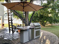 Outdoor kitchen setup with grill, table, and umbrella on a patio