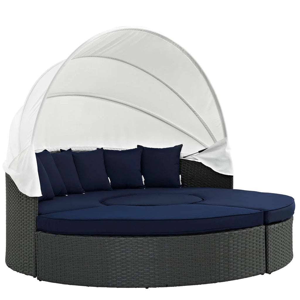 Round outdoor daybed with canopy and navy cushions on a white background
