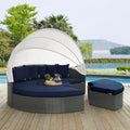Outdoor patio daybed with canopy and navy cushions by a poolside.