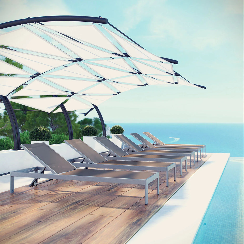 Row of lounge chaise chairs under a canopy by a pool with ocean view