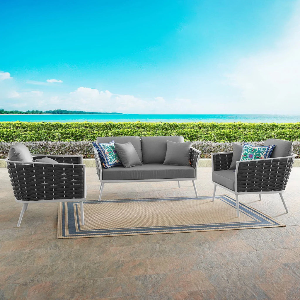 Outdoor patio set with gray cushions and black frames on a patio with a scenic background.