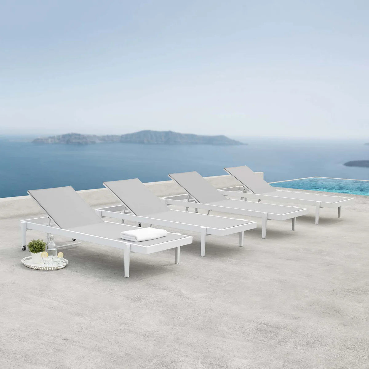 White lounge chairs on a terrace with a scenic ocean view