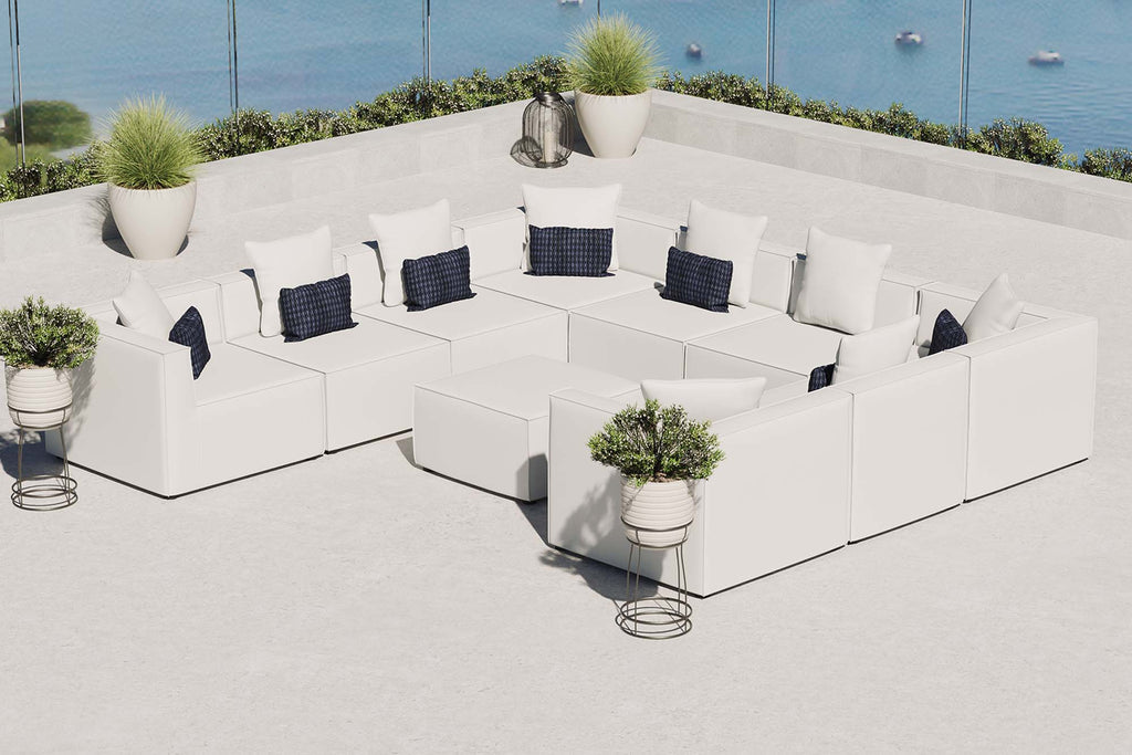 Modern outdoor seating area with white furniture, blue cushions, and potted plants by a waterfront.