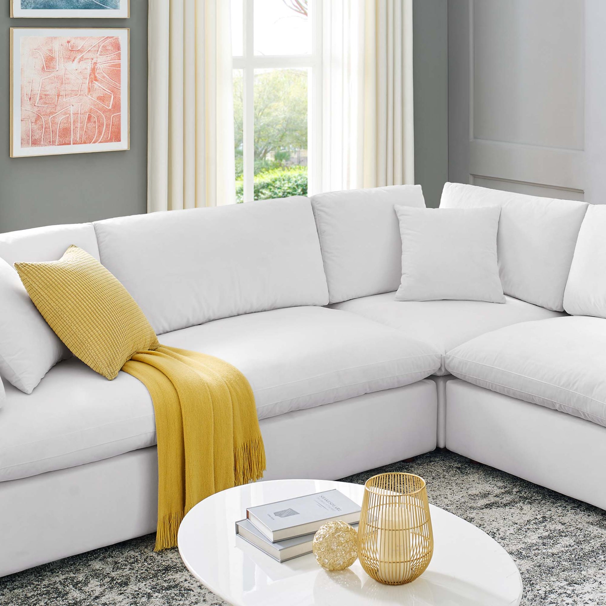 Modern living room with a white sectional sofa, yellow throw blanket, and decorative items.