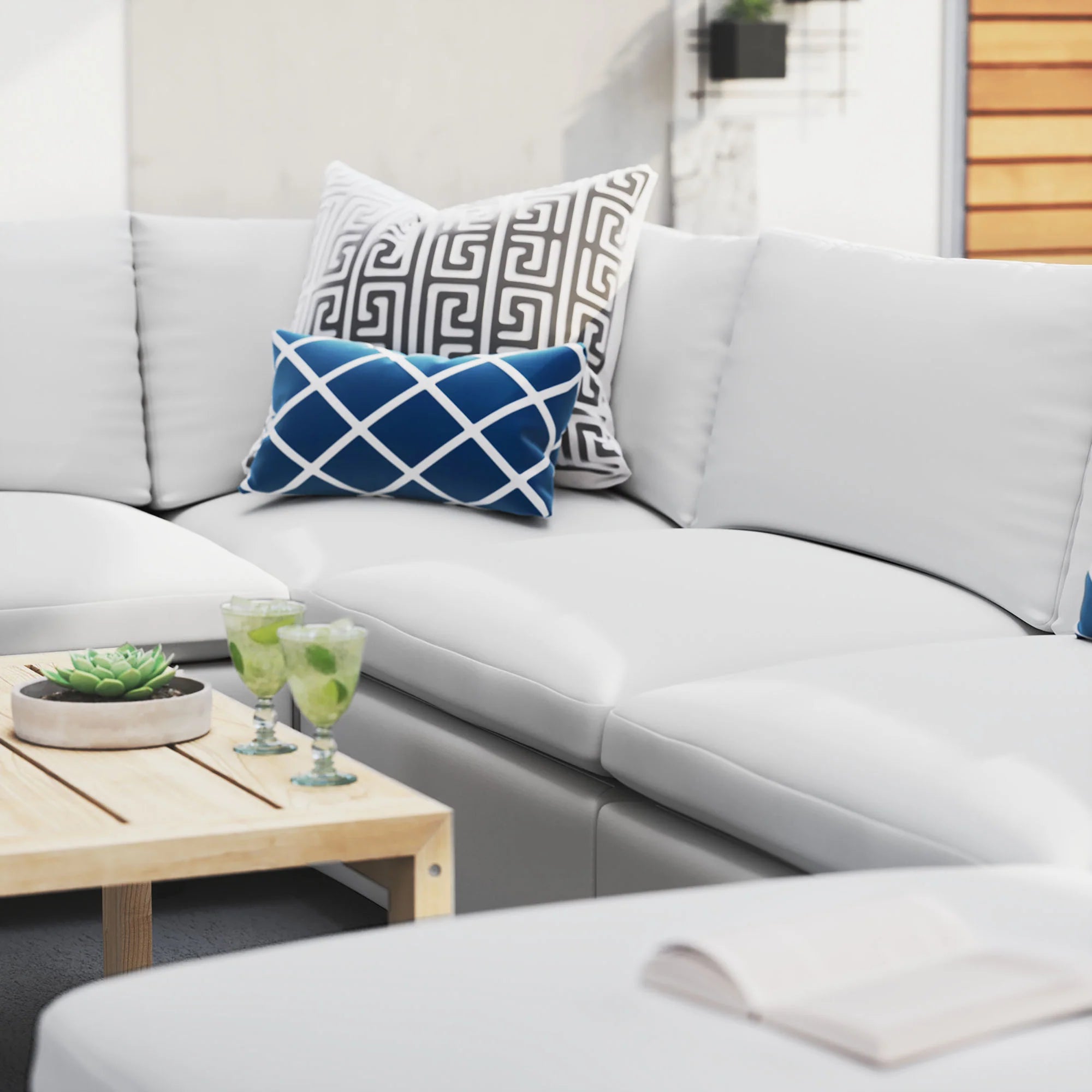 White sectional sofa with decorative pillows and a wooden coffee table in an outdoor setting.