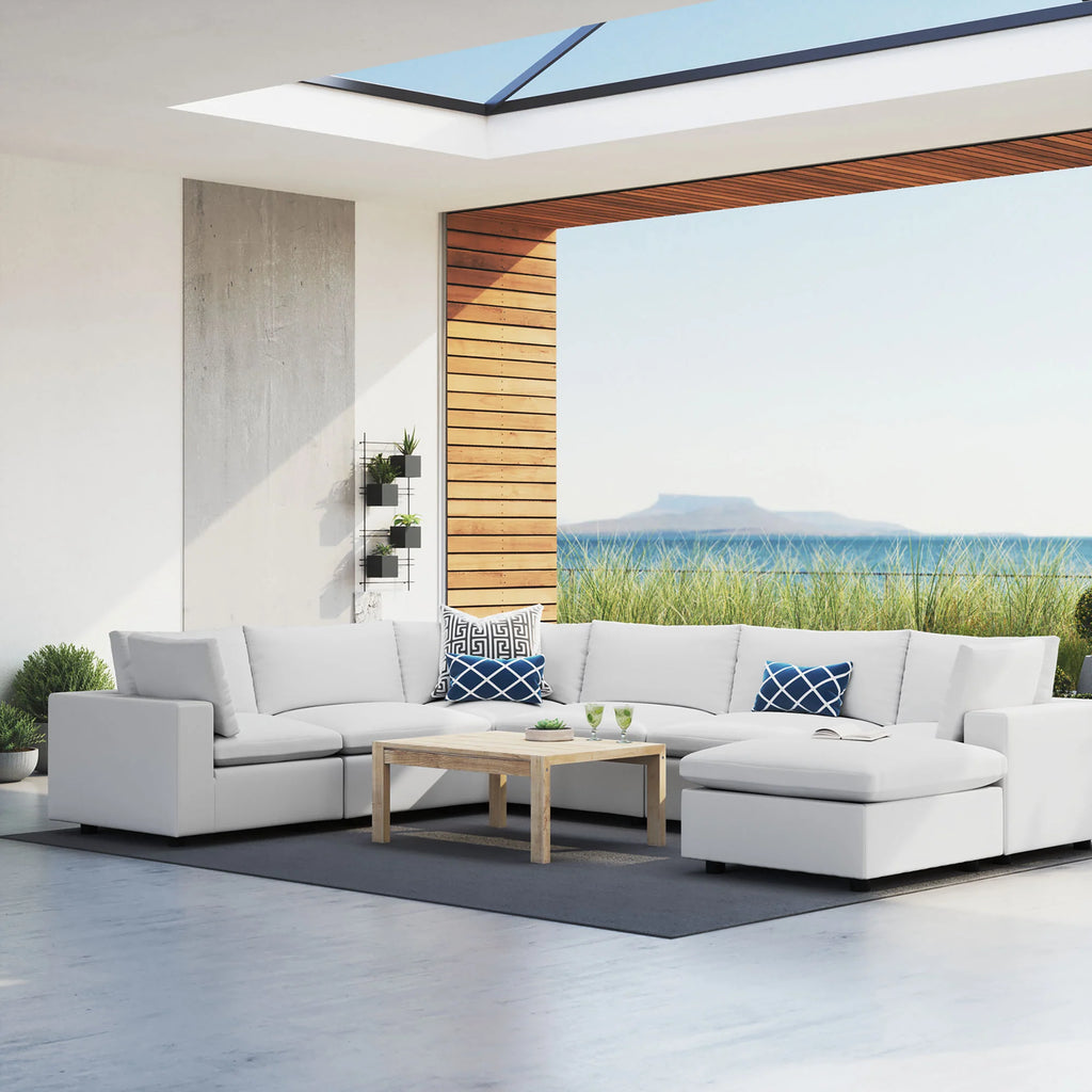 Modern outdoor patio with a sectional sofa, coffee table, and scenic view of water.