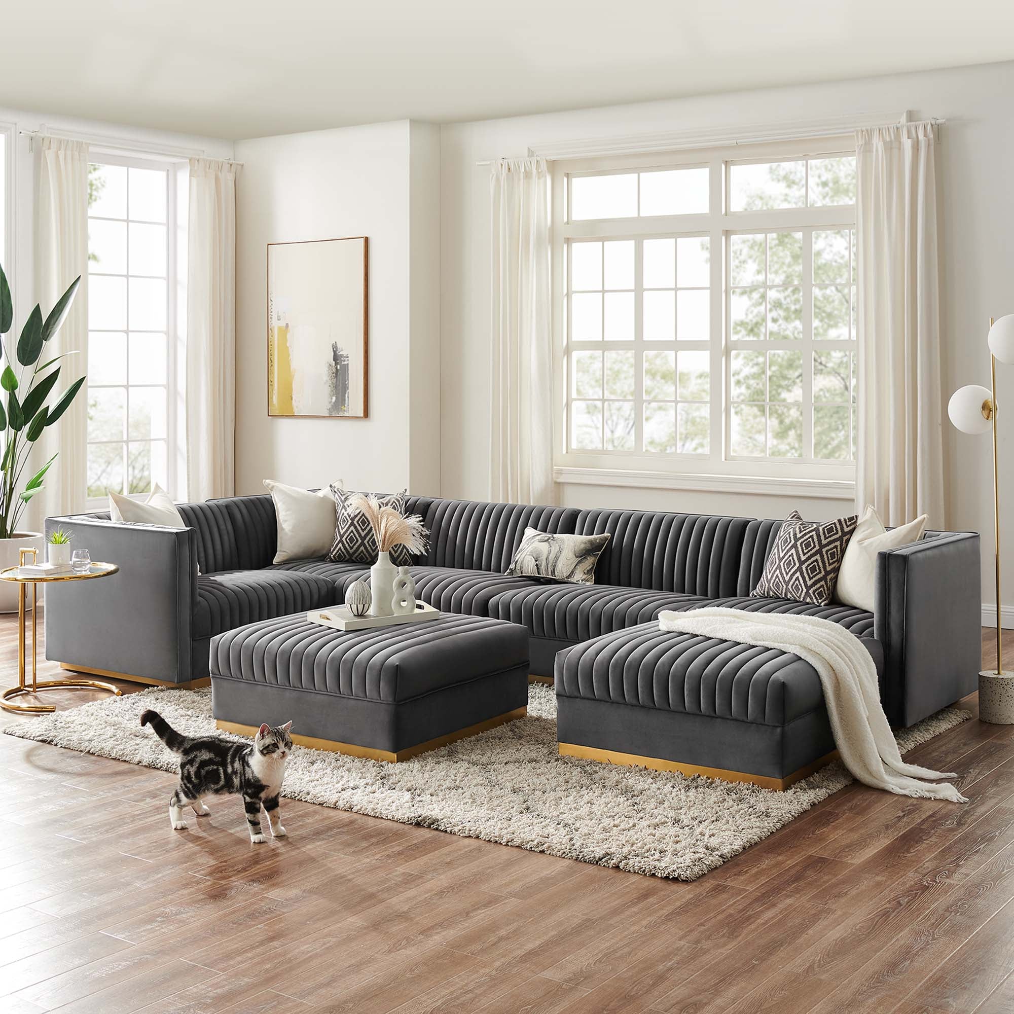 Gray sectional sofa in a living room with a cat walking on the rug.