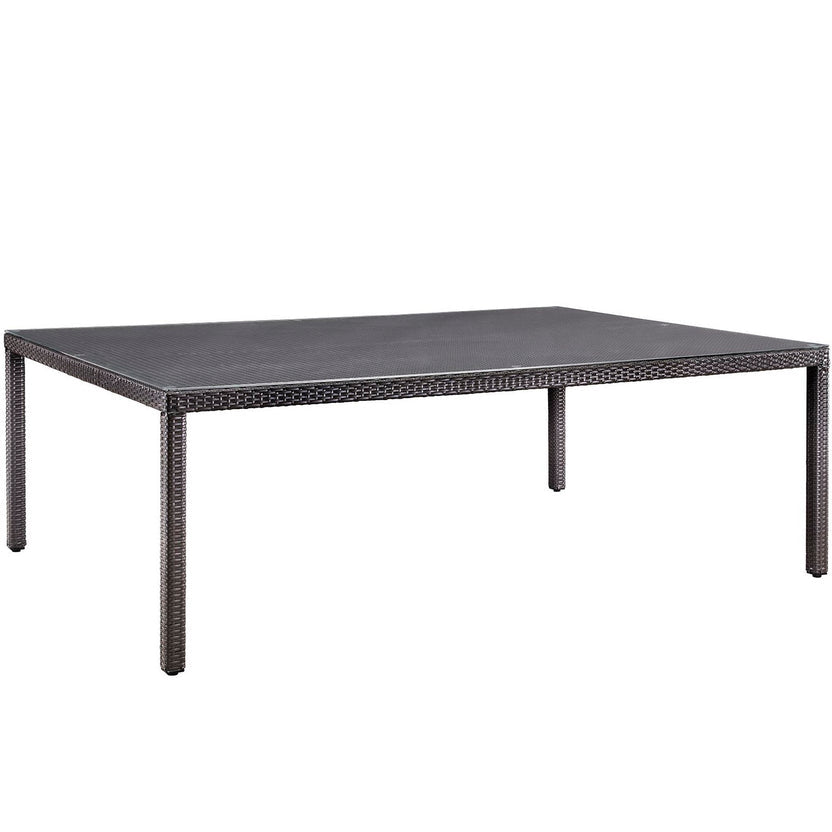 Rectangular outdoor table with dark surface and brown woven frame on a white background