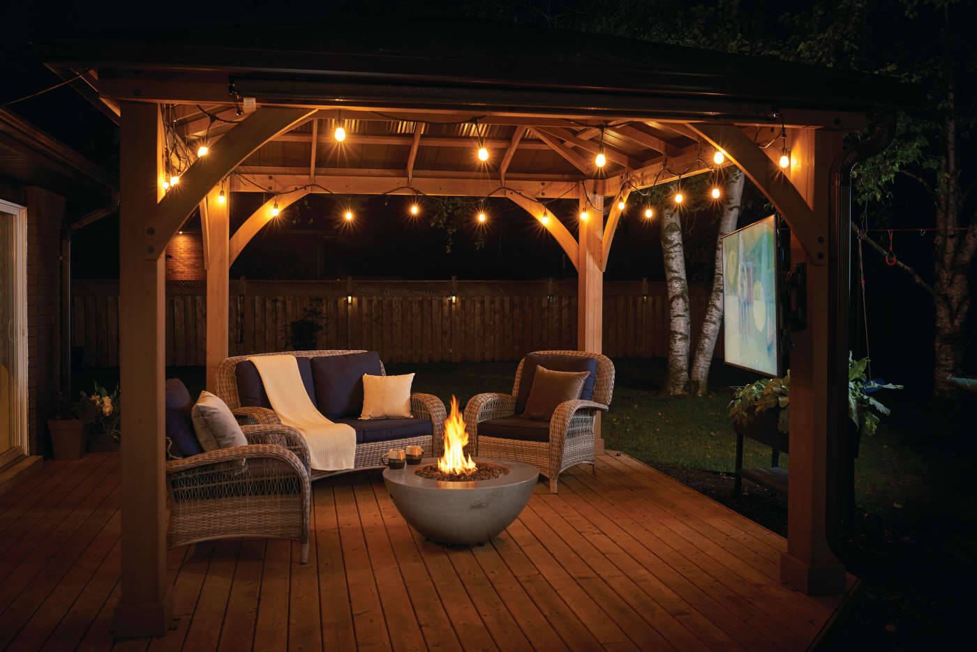 Outdoor patioflame table with wooden pergola, seating area, and fire pit at night.