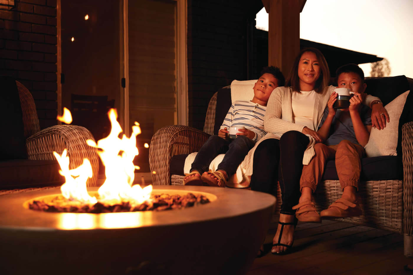 Family sitting on a couch by a fire pit at night