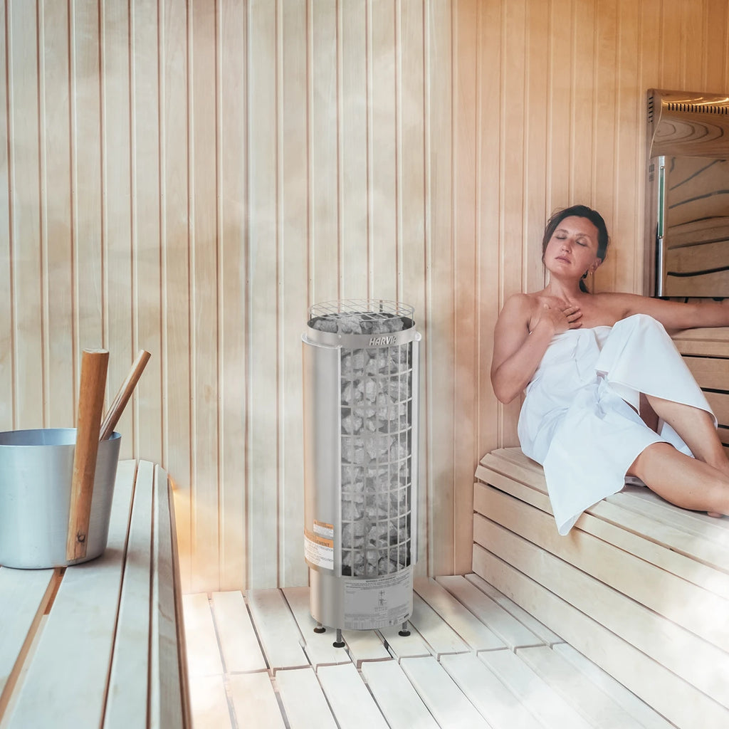 Harvia sauna heater with WiFi control in a wooden sauna with a relaxing woman seated nearby.