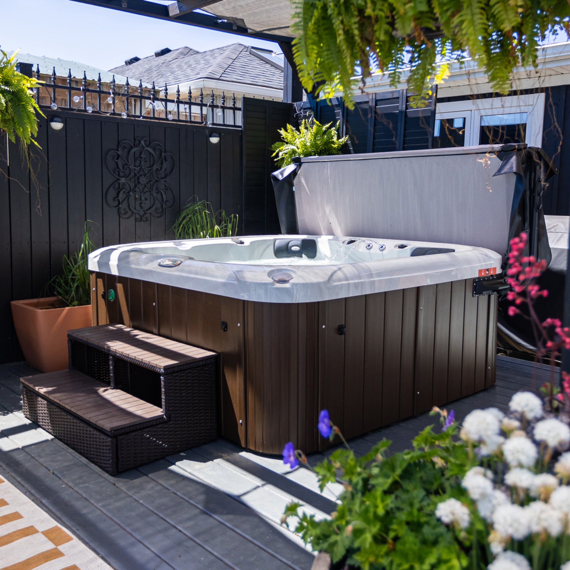 Hot tub on a patio with plants and flowers around