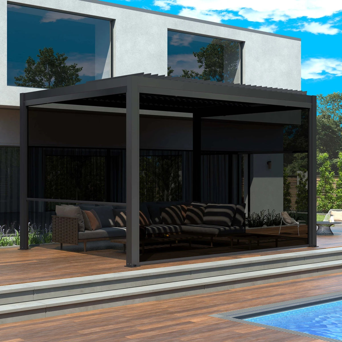 A modern dark gray outdoor patio cabana with a built-in sofa and cushions, situated on a wooden deck next to a swimming pool in front of a contemporary house.