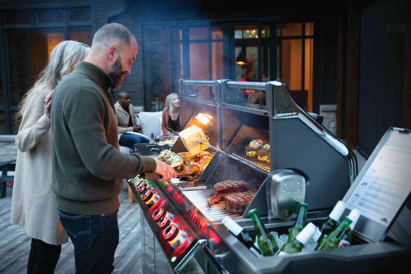 People grilling food on a barbecue grill outdoors at night.
