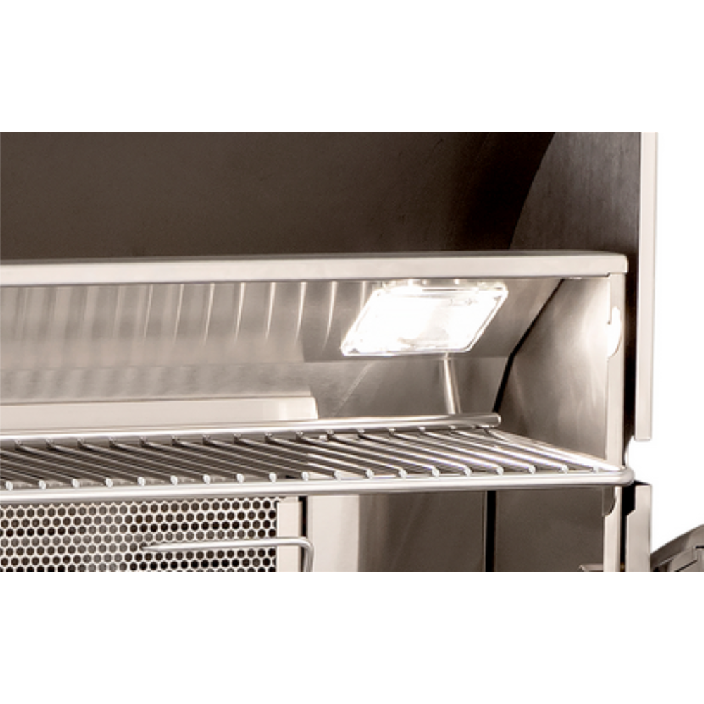Close-up of a stainless steel grill interior showing a wire shelf, perforated lower section, and a built-in light bulb illuminated on the upper shelf.