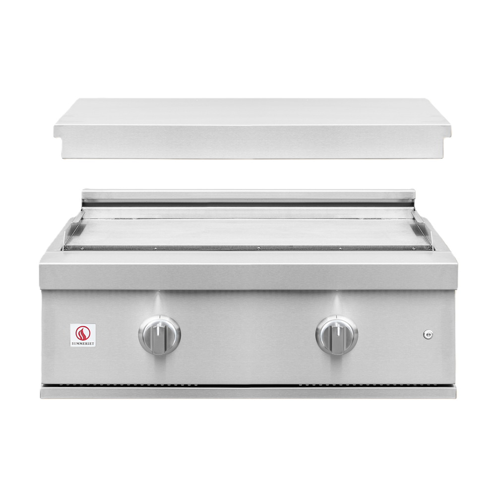 A stainless steel outdoor gas grill with a flat griddle plate, two control knobs, and a small red and white logo badge on the lower left front panel, shown against a plain white background.