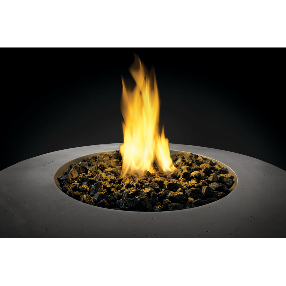 A circular concrete fire pit with a glowing yellow and orange flame rising over dark decorative stones, shown against a black background.