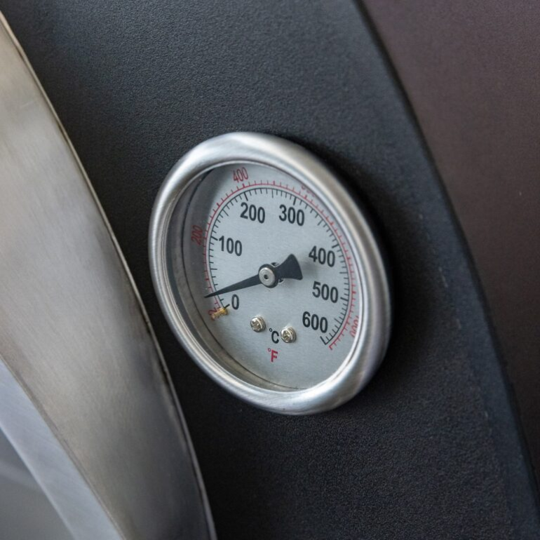 Temperature gauge on a grill showing Fahrenheit and Celsius readings
