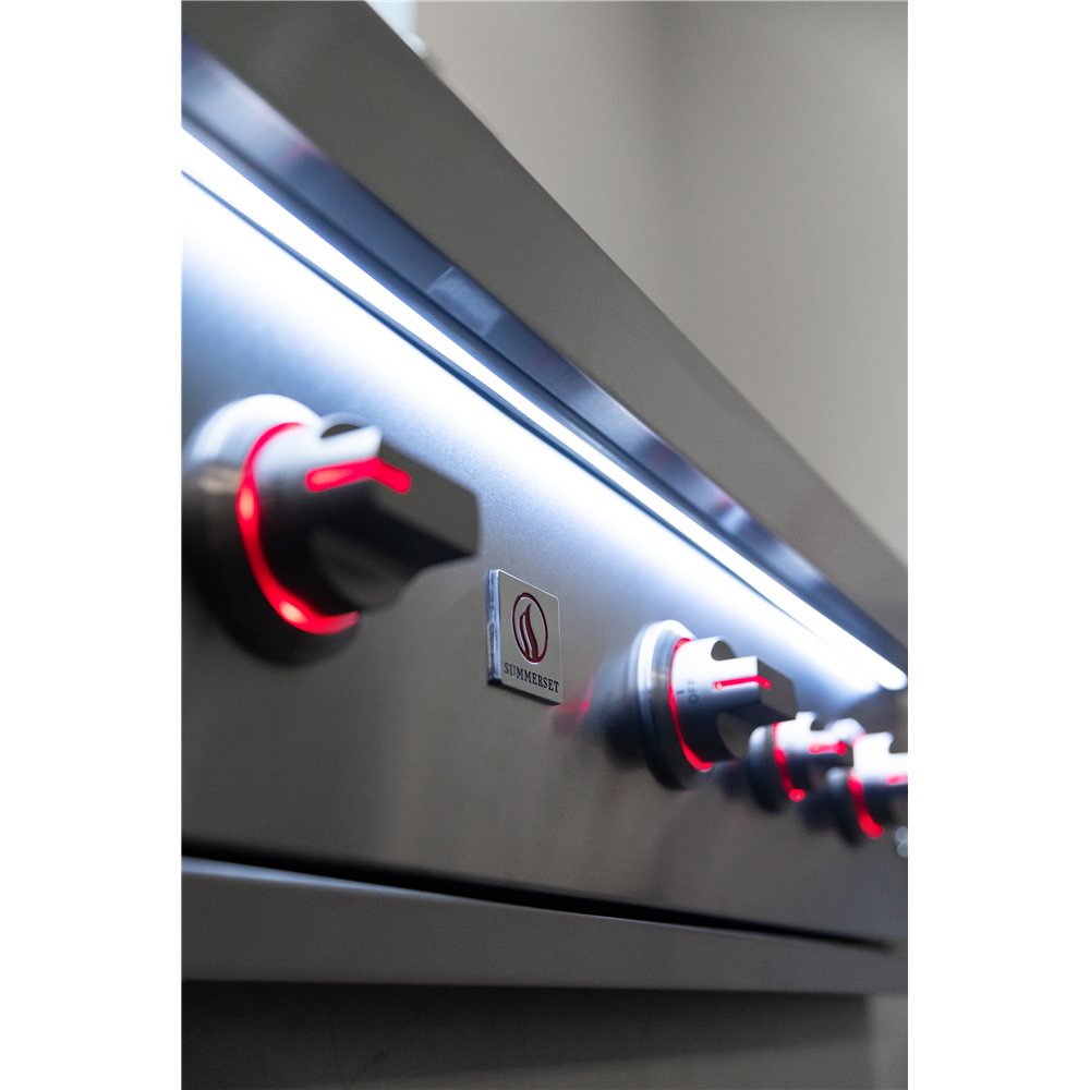 Close-up of a gas stove with control knobs and brand logo.