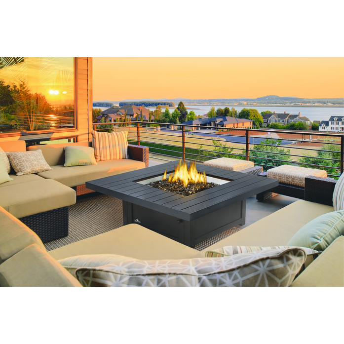 Outdoor patio with fire pit table and sectional sofa during sunset.