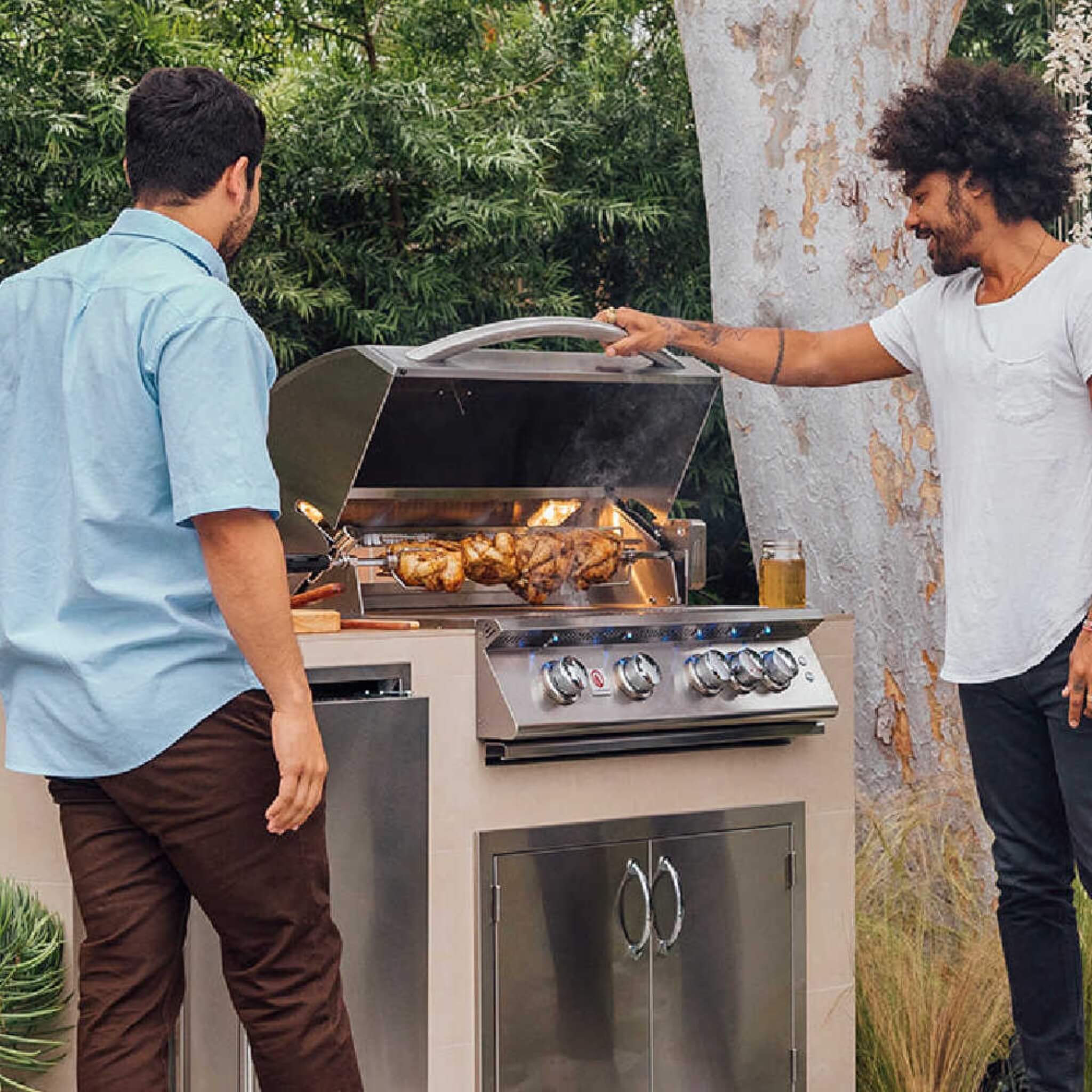 Two men grilling outdoors on a stainless steel barbecue grill