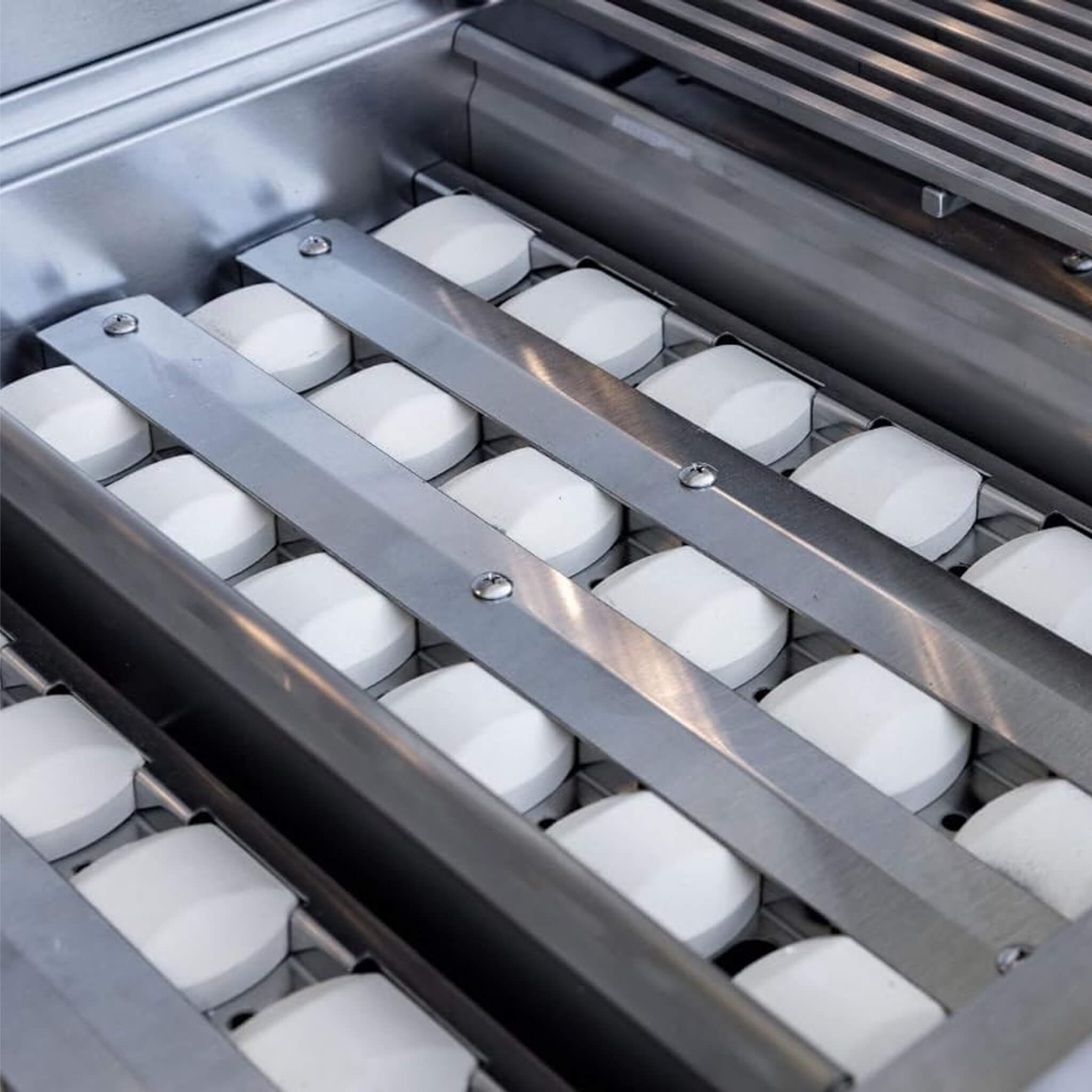 Metallic grill with white ceramic briquettes on a gray background