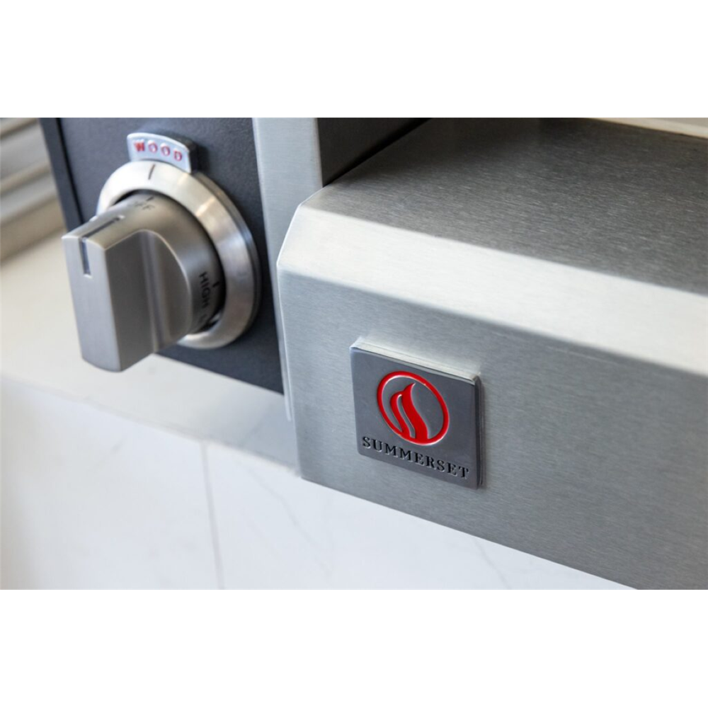 Close-up of a stainless steel appliance showing a silver rotary dial and a square SUMMERSET logo badge with a red flame emblem on the side.